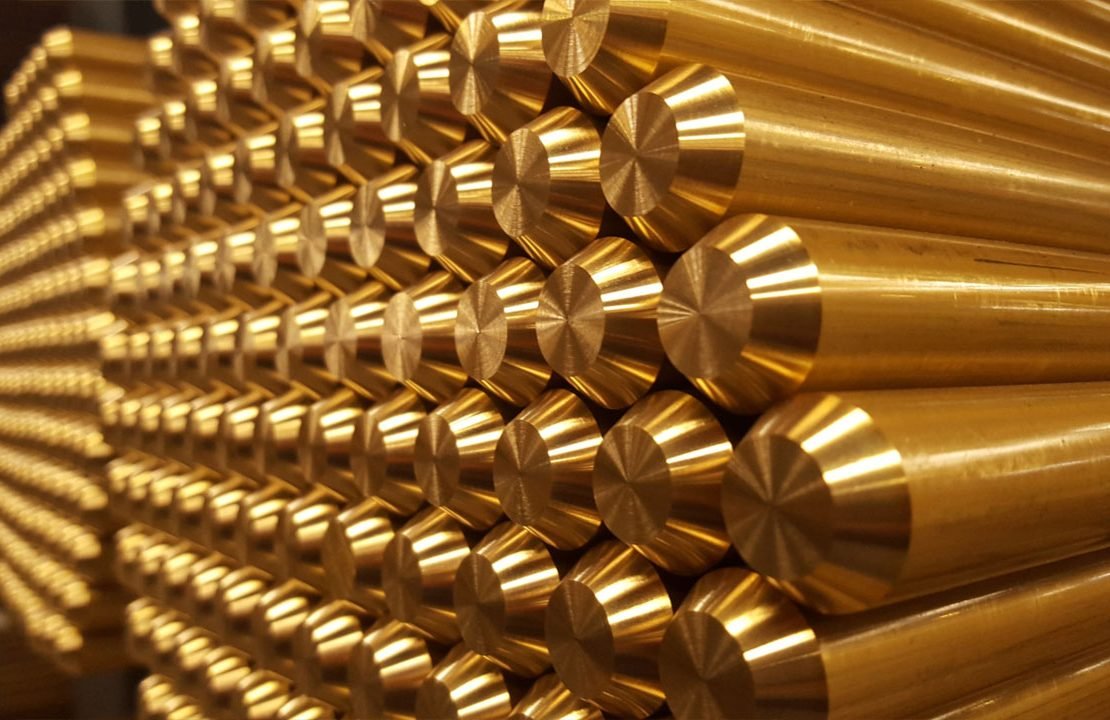 Stacks of shiny brass rods aligned horizontally, showcasing their cylindrical shape and metallic finish.