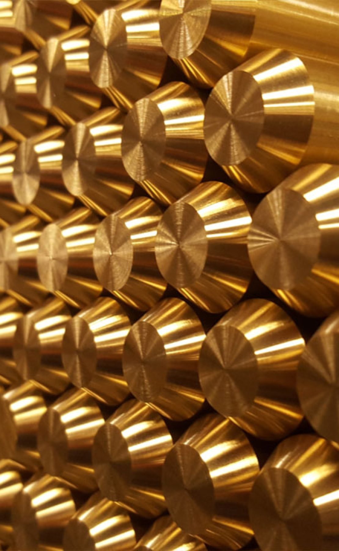 Stacks of shiny brass rods aligned horizontally, showcasing their cylindrical shape and metallic finish.